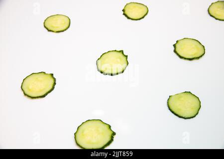 A closeup shot of scattered sliced cucumbers isolated on a white background Stock Photo