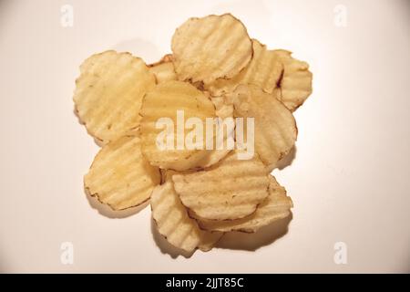 A heap of fried potato chips isolated on a pink background Stock Photo