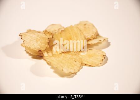 A heap of fried potato chips isolated on a pink background Stock Photo