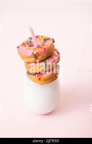 A glass of milk with tasty donuts isolated on a pink background Stock Photo