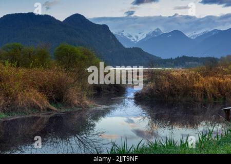 A beautiful shot of a wild lake reflecting the environment in the background of mountains Stock Photo