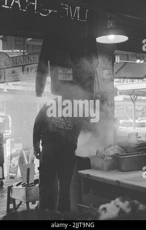 A grayscale shot of a chief in the kitchen cooking the clam chowder in the restaurant in Pike Place Market, Seattle, Washington, United State Stock Photo