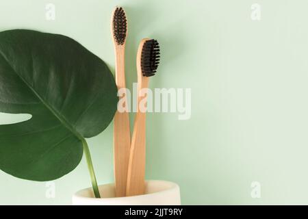Zero waste Top view natural eco bamboo toothbrush with monstera leaves top view Stock Photo