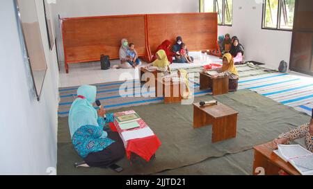 A group of students studying the Koran with their female teacher in Batang, Indonesia Stock Photo