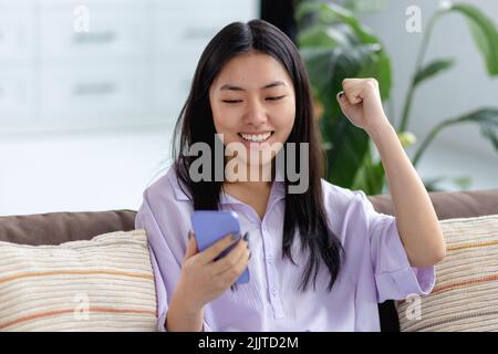 Excited young woman using mobile phone shopping online Big sales concept Stock Photo