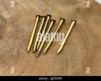 The heap of steel brass nails on a wooden surface Stock Photo