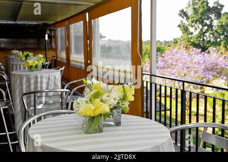 Beautiful cafe tables with flowers with a view of a sunny garden Stock Photo