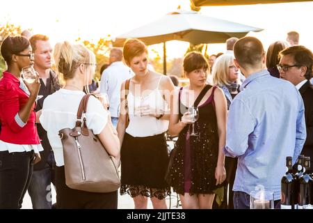 Diverse people socializing at an outdoor cocktail party in Johannesburg Stock Photo