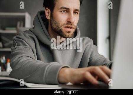 Young beard man working with laptop while sitting at desk in office Stock Photo
