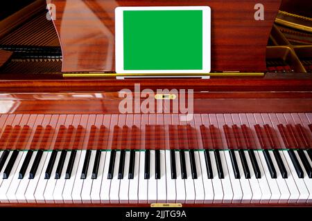 On the piano there is a tablet with an empty field, chroma key. Music festival mockup Stock Photo