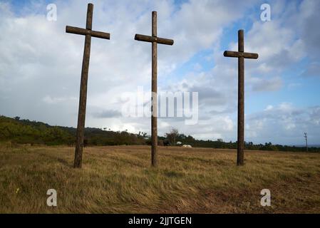 A low angle of three wooden crosses in the field against blue sky background Stock Photo