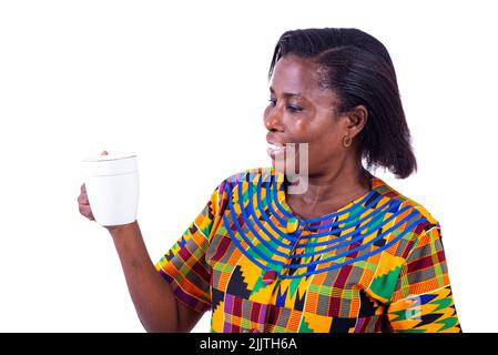 portrait of an adult woman standing and looking at a cup of coffee in hand while smiling. Stock Photo