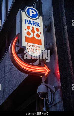 A parking sign with a neon red arrow on a building Stock Photo