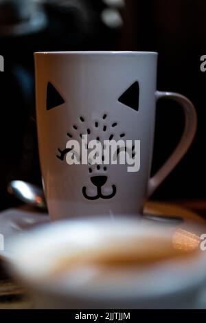 A white cup designed with kitten face on a table Stock Photo