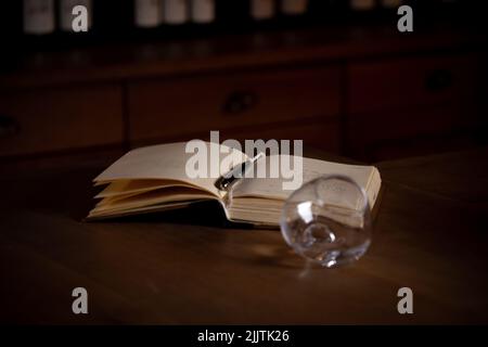 A selective focus shot of open diary with pen next to a glass on wooden table Stock Photo