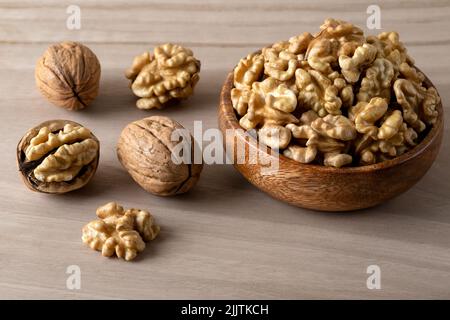 Whole shelled walnuts and cracked walnuts on wooden background Stock Photo