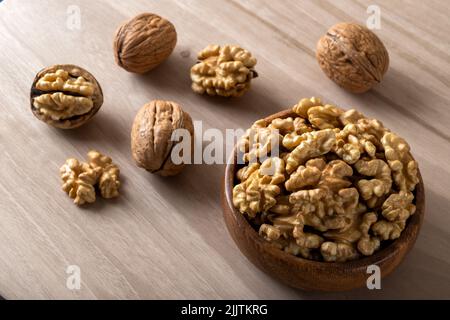 Whole shelled walnuts and cracked walnuts on wooden background Stock Photo
