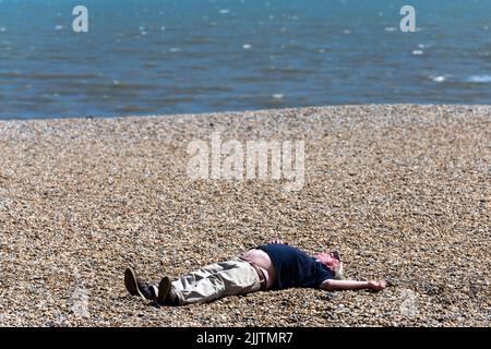 Man sunbathing on the beach during the hot summer of 2022 Stock Photo