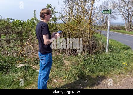 A side view of male wearing glasses standing and holding a drone controller Stock Photo