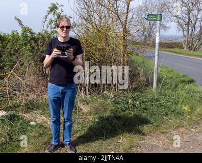 A male wearing glasses standing and holding a drone controller Stock Photo