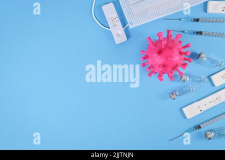 Tools to fight Corona Virus pandemic. Rapid antigen test, medical face masks, vaccine vials with syringes on blue bakcground with copy space Stock Photo