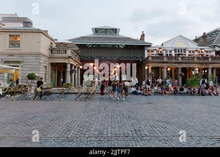 London, Greater London, England, July 20 2022: People sit and relax in the main square of Convent garden, famous for its street acts and market and ch