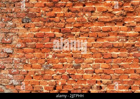 Old red uneven brick wall. Vintage background. Abstract texture. Stock Photo