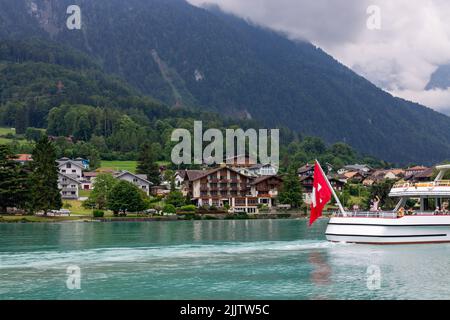 The boat on Lake Brienz passing by the small town surrounded by the Alps. Interlaken, Switzerland. Stock Photo