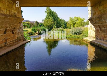 River Ucero passing under the medieval bridge that gives entrance to the old city of Burgo de Osma. Stock Photo