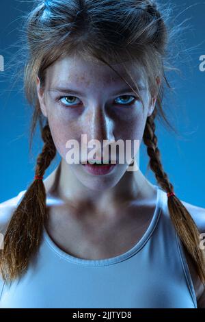 Motiovation for win. Young girl, MMA fighter in sports uniform isolated on blue background. Concept of sport, competition, action, healthy lifestyle. Stock Photo