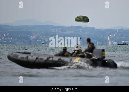 Langenargen Am Bodensee, Germany. 28th July, 2022. Paratroopers of the German Armed Forces land with their parachutes off Langenargen in Lake Constance to practice water landings. Shortly afterwards, the paratroopers are taken out of the water by comrades in rubber dinghies. Credit: Felix Kästle/dpa/Alamy Live News Stock Photo