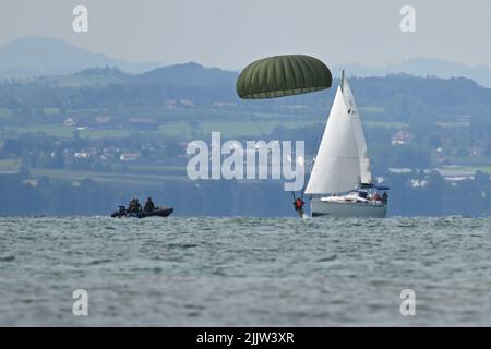 Langenargen Am Bodensee, Germany. 28th July, 2022. Paratroopers of the German Armed Forces land with their parachutes off Langenargen in Lake Constance to practice water landings. Shortly afterwards, the paratroopers are taken out of the water by comrades in rubber dinghies. Credit: Felix Kästle/dpa/Alamy Live News Stock Photo