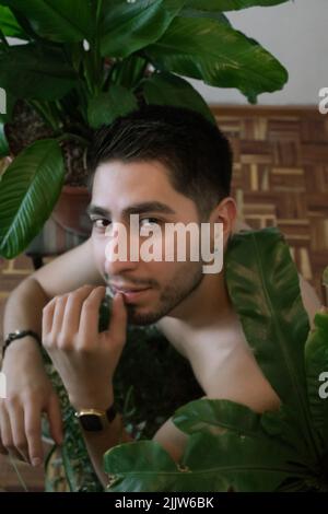 Close up of young mexican man with short hair surrounded by plants Stock Photo