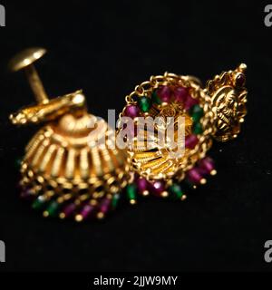 antique earrings called jhumkas made of gold with precious stones from a vintage collection isolated in a black background Stock Photo