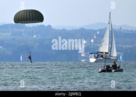 Langenargen Am Bodensee, Germany. 28th July, 2022. Paratroopers land with their parachutes off Langenargen in Lake Constance to practice water landings while a boat sails over Lake Constance. Shortly afterwards, the paratroopers are pulled out of the water by comrades in rubber dinghies. Credit: Felix Kästle/dpa/Alamy Live News Stock Photo