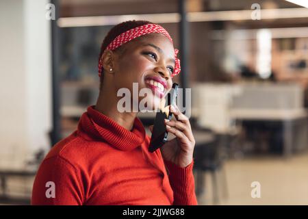Happy african american businesswoman talking on smart phone in creative office Stock Photo