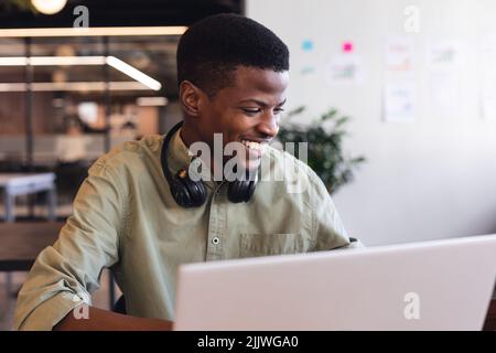 Smiling african american young businessman using laptop in office Stock Photo