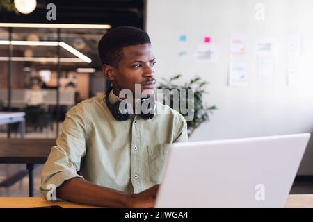 Thoughtful african american young businessman with laptop in office Stock Photo