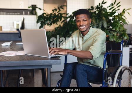 Portrait of smiling african american businessman with disability using laptop in wheelchair Stock Photo