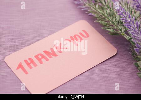 thank you message on sticky note and flower on purple background  Stock Photo