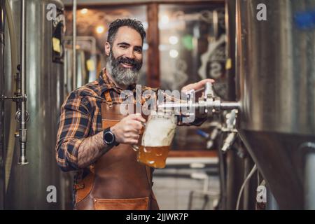 Brewery master tasting beer in production facility. Small family business, production of craft beer. Stock Photo
