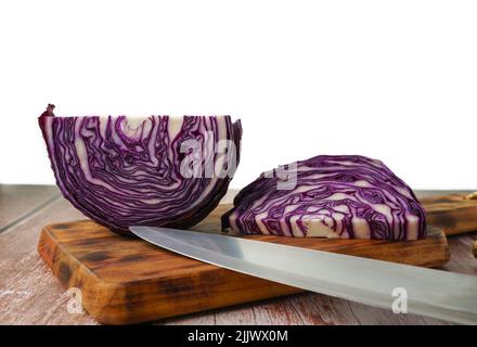 close-up of a red cabbage or purple cabbage cut with a knife on a wooden board Stock Photo