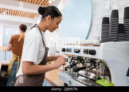 African american barista making coffee near machine in confectionery Stock Photo