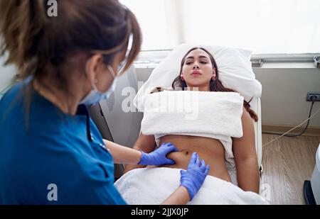 From above esthetician in latex gloves injecting collagen into lips of ...