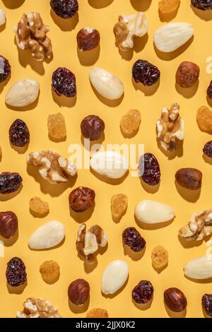 Top view assorted nuts and sweet raisins forming seamless pattern on yellow background Stock Photo