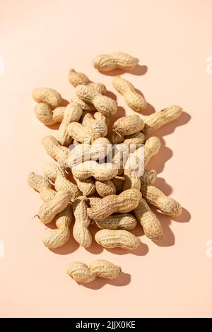 Top view pile of fresh peanuts in shells on peach background Stock Photo