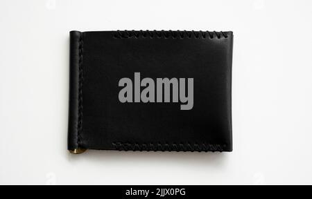 Black men's money clip handmade leather wallet for cards lies on a white table. Leather goods and accessory. Stock Photo