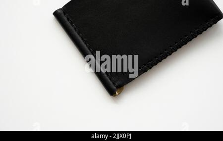 Black men's money clip handmade leather wallet for cards lies on a white table. Leather goods and accessory. Stock Photo