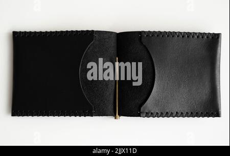 Open black men's money clip handmade leather wallet for cards lies on a white table. Leather goods and accessory. Stock Photo