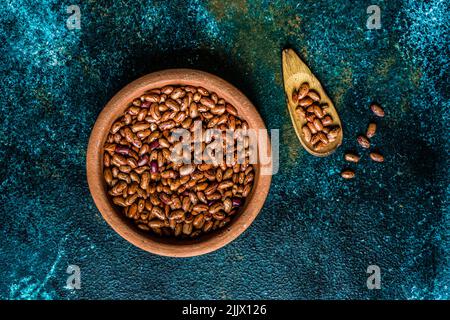 Overhead ceramic bowl with red kidney beans on dark green concrete background Stock Photo